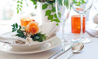 Ein sehr edel gedeckter Tisch mit Servietten, Rosen und Silberbesteck.