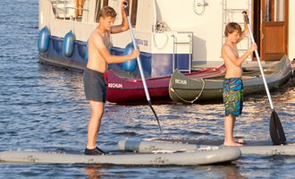 Kanu und SUP Verleih im Hafendorf Müritz, im Hintergrund ein Hausboot Kormoran 