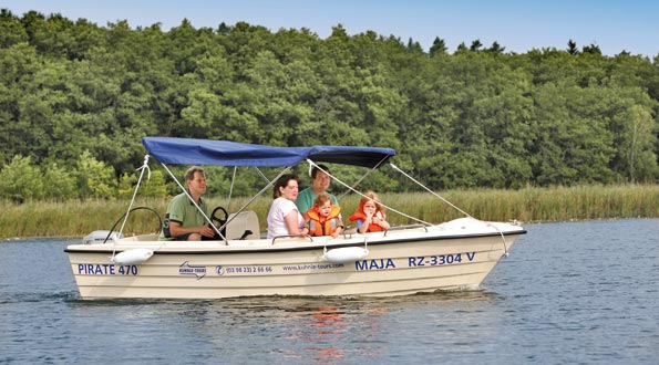 Eine Familie fährt mit einem kleinen Motorboot über einen See. Sie sind geschützt durch ein Sonnendach.